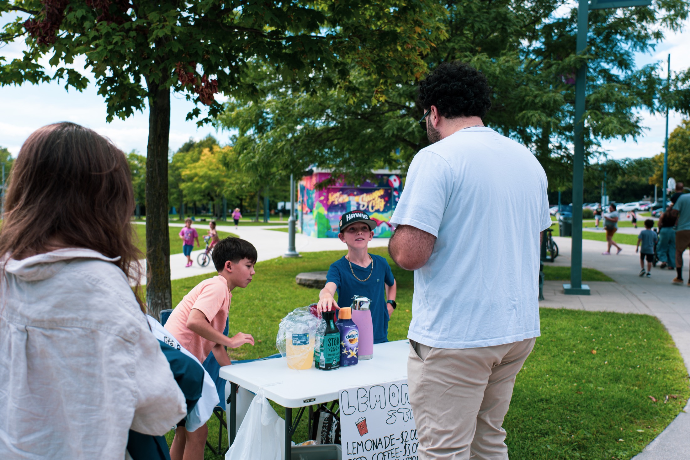Jad El Ghali speaking with young community members at a neighbourhood lemonade stand