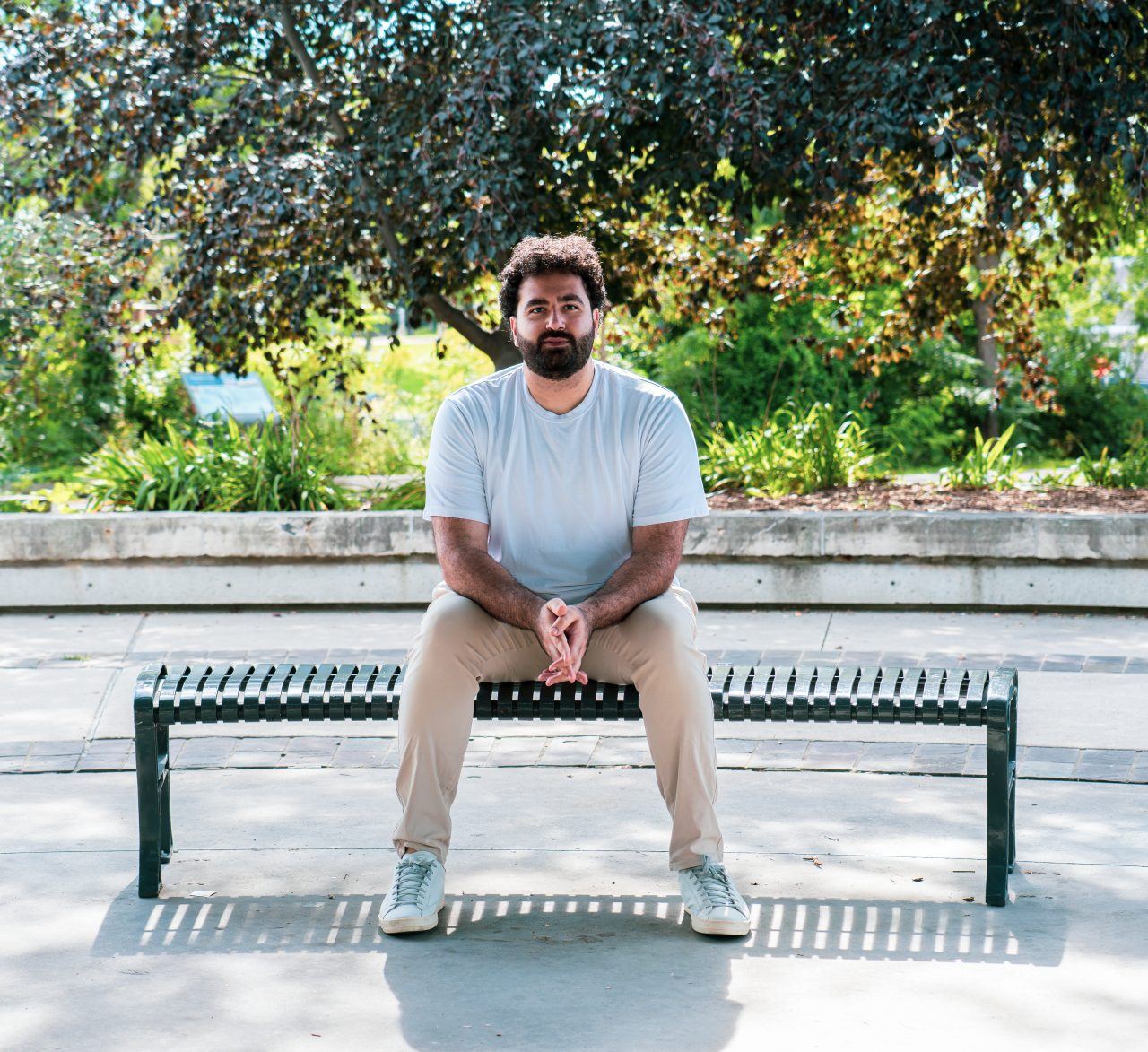 Jad El Ghali facing the camera while seated on a park bench in Mississauga